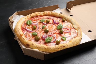 Photo of Delicious vegetarian pizza in box on black table, closeup