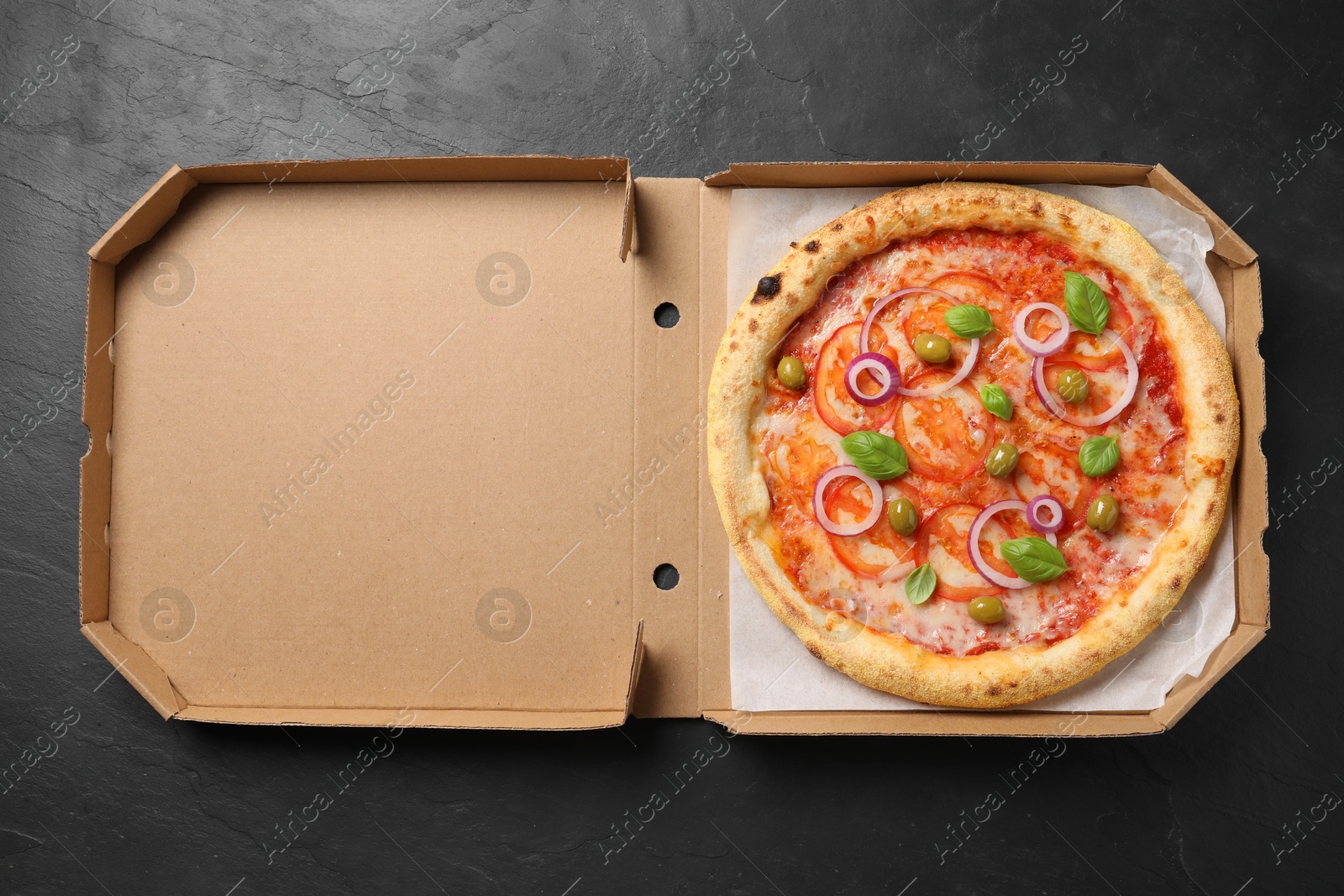 Photo of Delicious vegetarian pizza in box on black table, top view