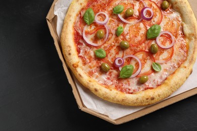 Photo of Delicious vegetarian pizza in box on black table, top view