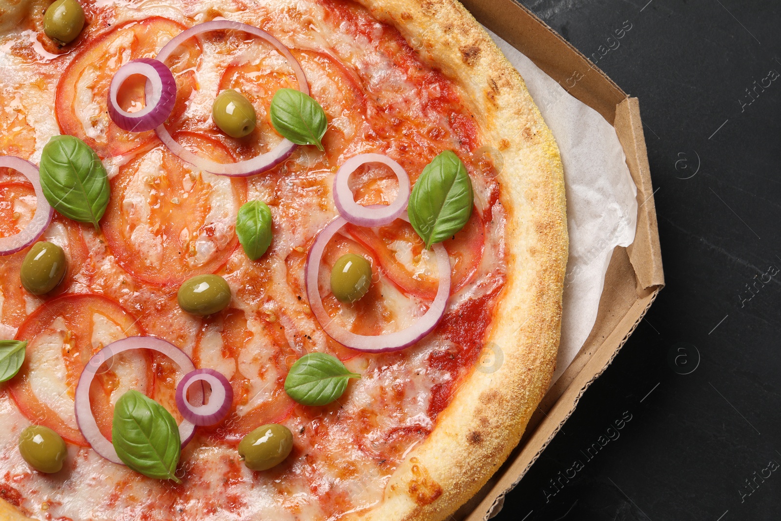 Photo of Delicious vegetarian pizza in box on black table, closeup