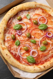 Photo of Delicious vegetarian pizza in box on black table, top view