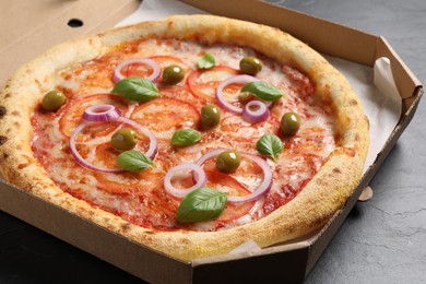 Photo of Delicious vegetarian pizza in box on black table, closeup