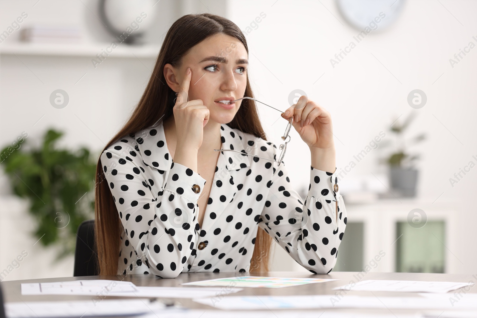 Photo of Embarrassed woman with glasses at table in office