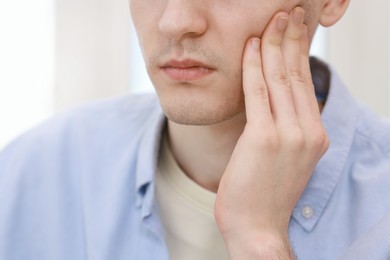 Man suffering from toothache at home, closeup