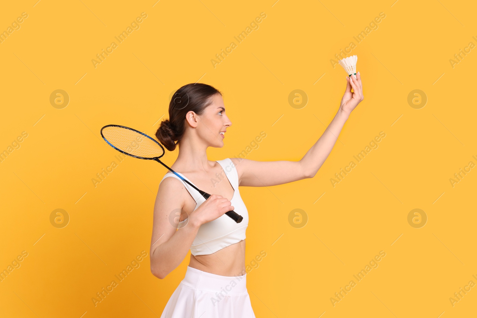 Photo of Young woman with badminton racket and shuttlecock on orange background