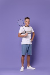 Young man with badminton racket on purple background
