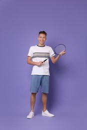 Photo of Young man with badminton racket on purple background