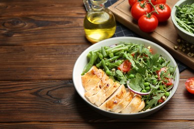 Photo of Healthy meal. Tasty salad and chicken breast in bowl on wooden table, space for text