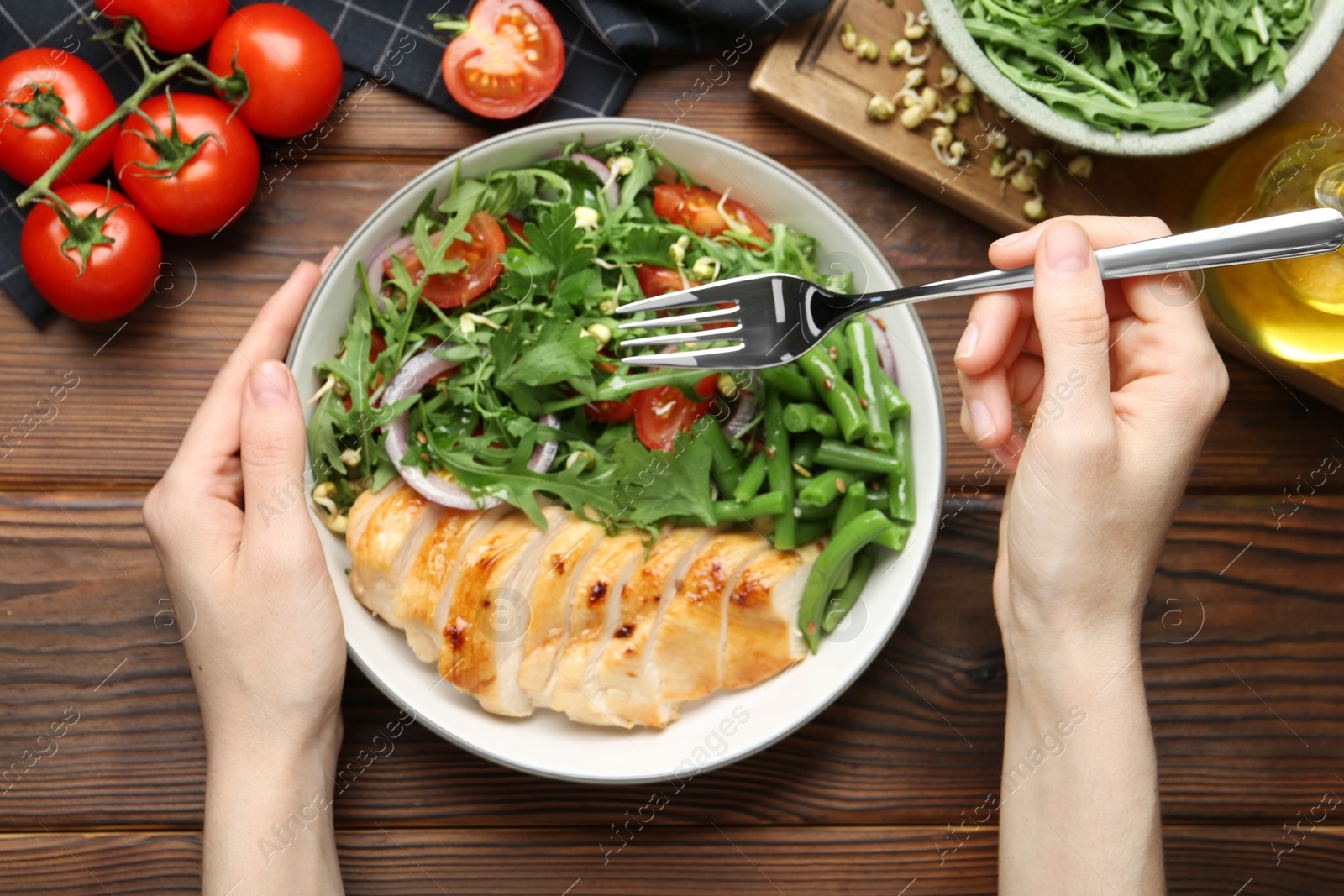 Photo of Healthy meal. Woman with bowl of tasty products at wooden table, top view