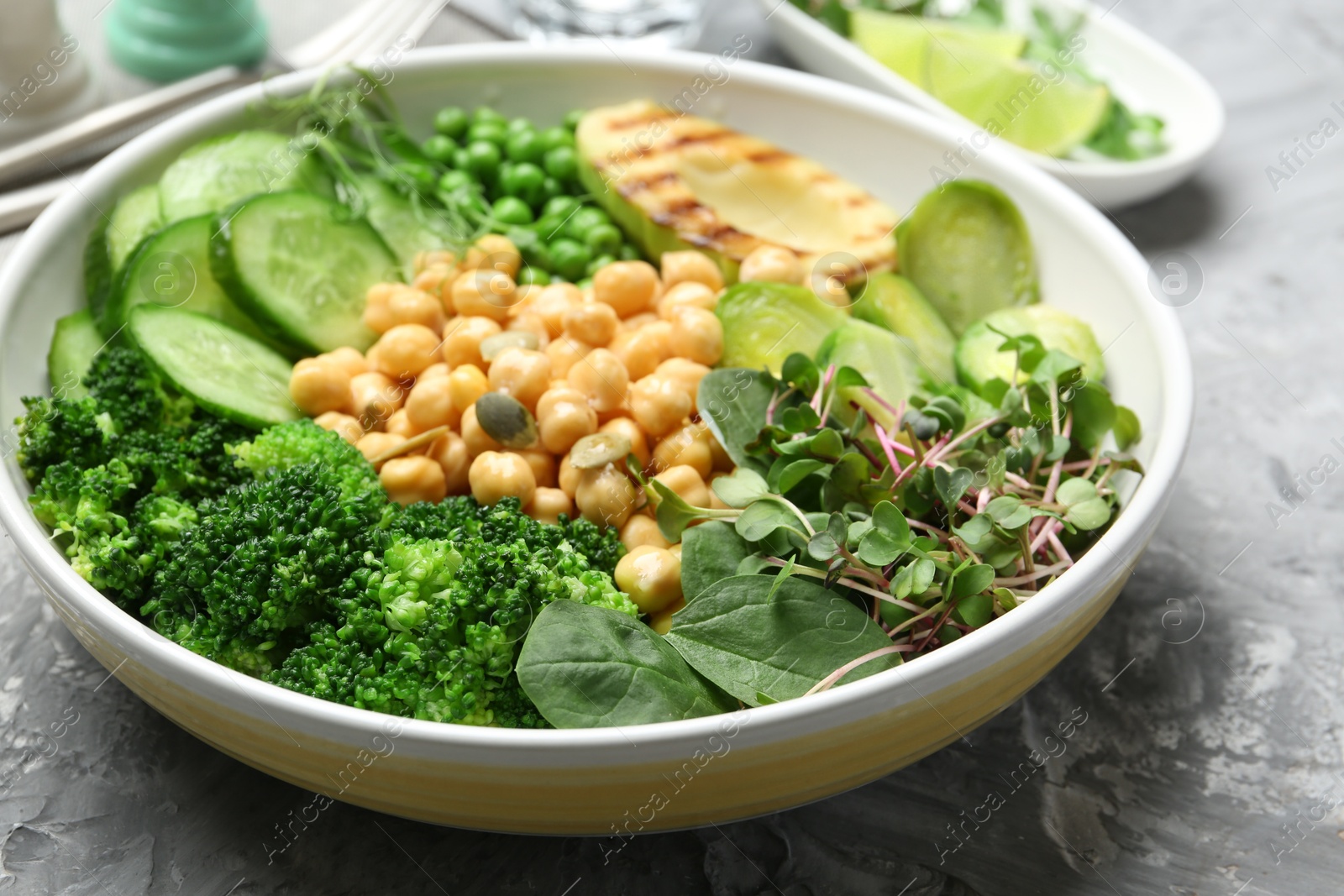 Photo of Healthy meal. Tasty vegetables and chickpeas in bowl on grey table, closeup