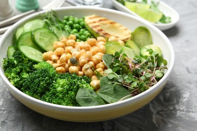 Photo of Healthy meal. Tasty vegetables and chickpeas in bowl on grey table, closeup