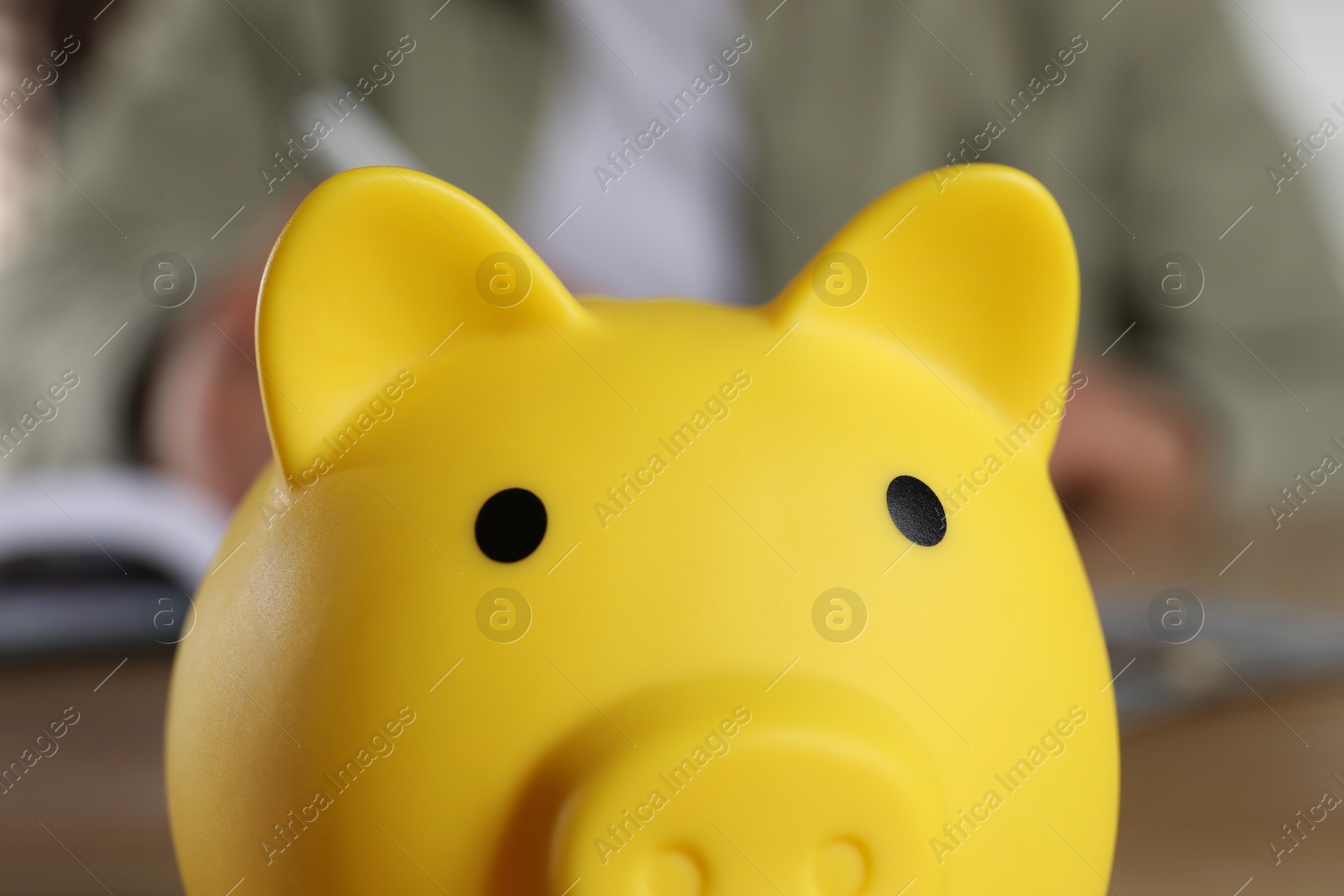 Photo of Yellow piggy bank on blurry background, closeup