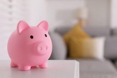 Photo of Pink piggy bank on white table, space for text