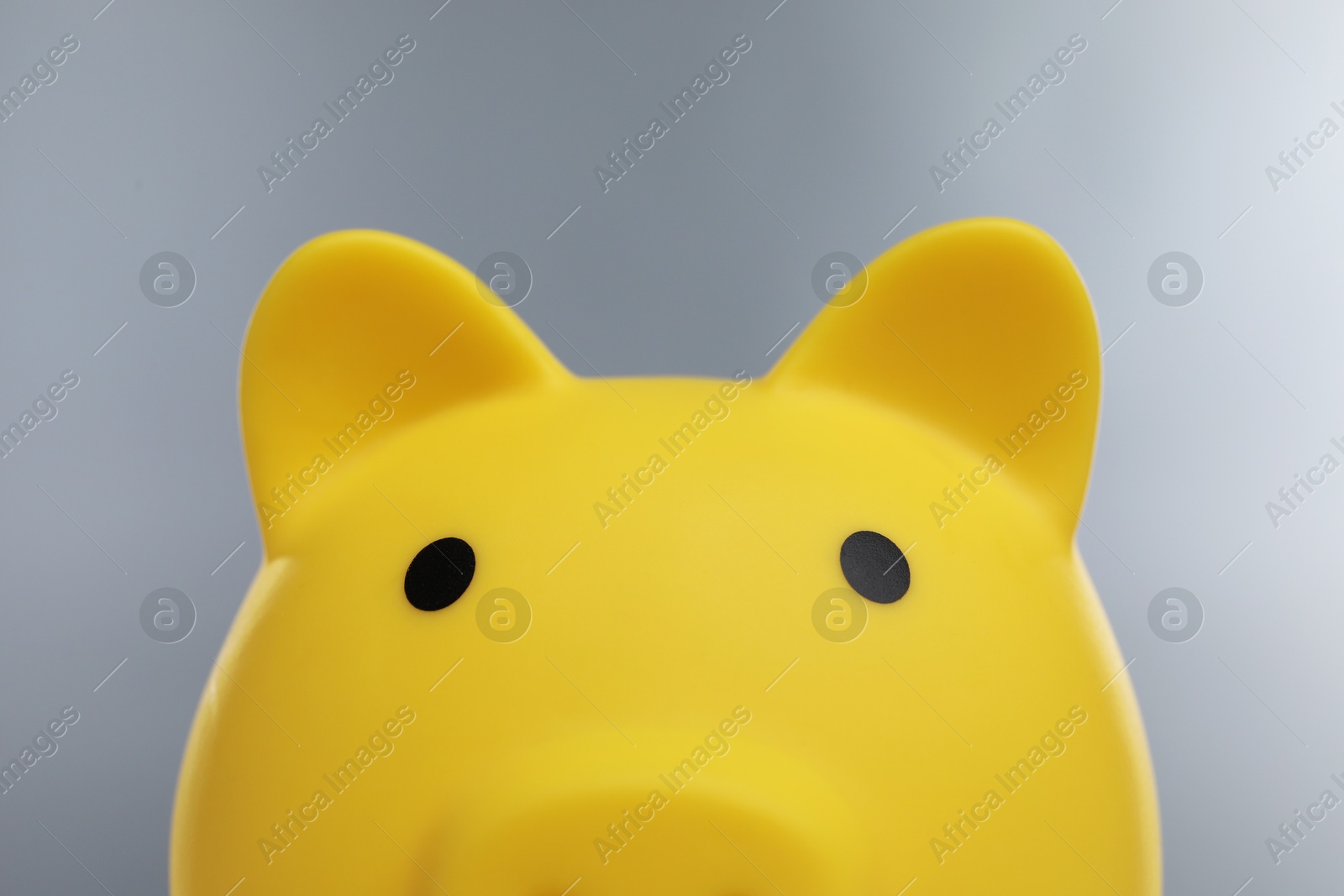 Photo of Yellow piggy bank on grey background, closeup