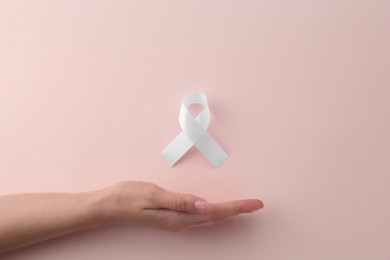 Photo of Woman with white awareness ribbon on beige background, top view