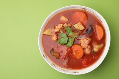 Delicious homemade stew in bowl on green background, top view. Space for text