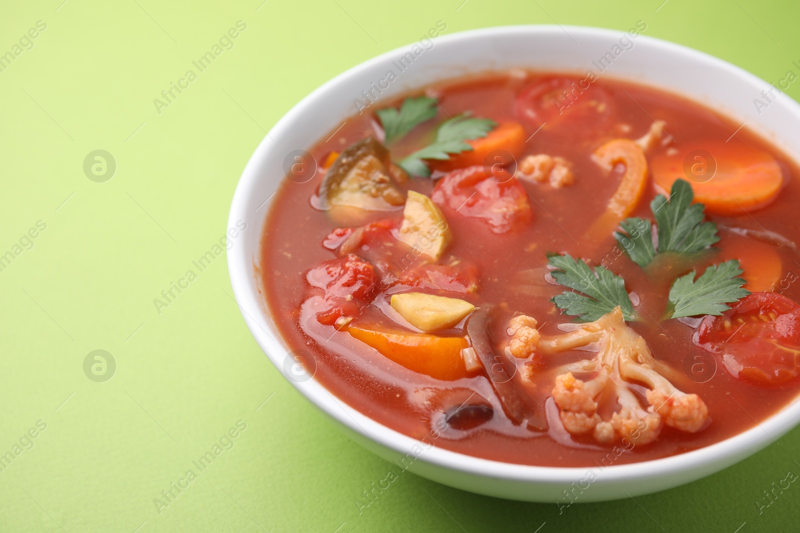 Photo of Delicious homemade stew in bowl on green background, closeup