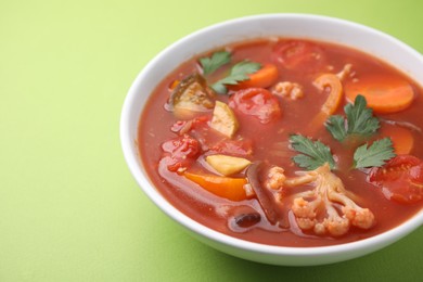 Delicious homemade stew in bowl on green background, closeup