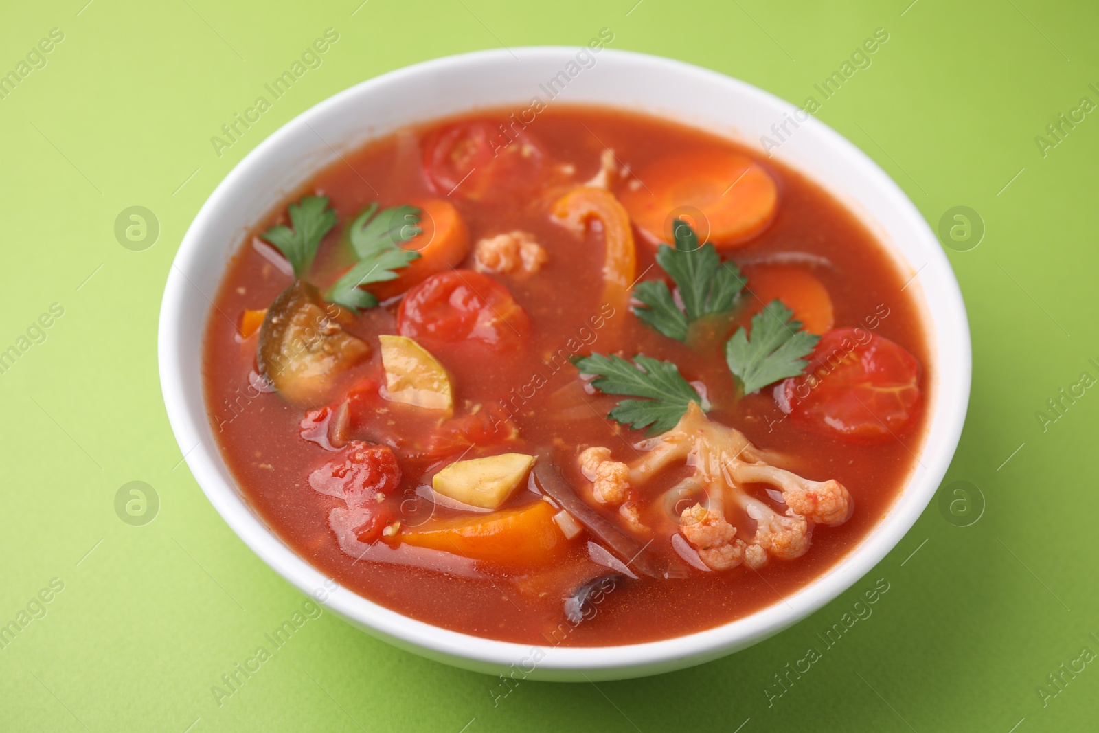 Photo of Delicious homemade stew in bowl on green background, closeup