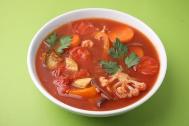 Delicious homemade stew in bowl on green background, closeup