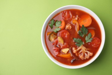 Delicious homemade stew in bowl on green background, top view. Space for text