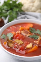 Delicious homemade stew in bowl on white table, closeup