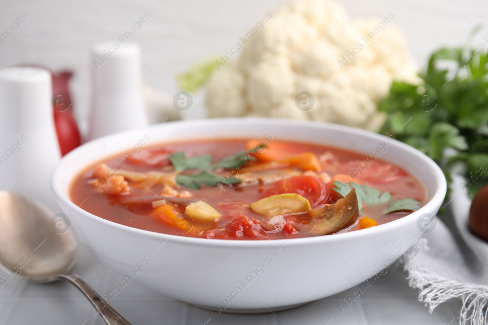 Photo of Delicious homemade stew in bowl on white tiled table, closeup