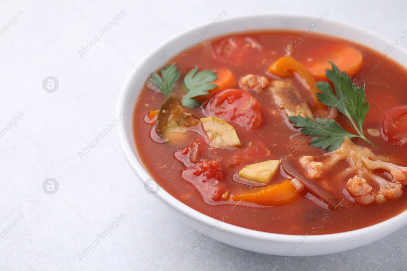 Photo of Delicious homemade stew in bowl on light table, closeup. Space for text