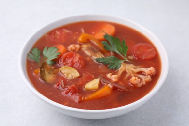 Delicious homemade stew in bowl on light table, closeup