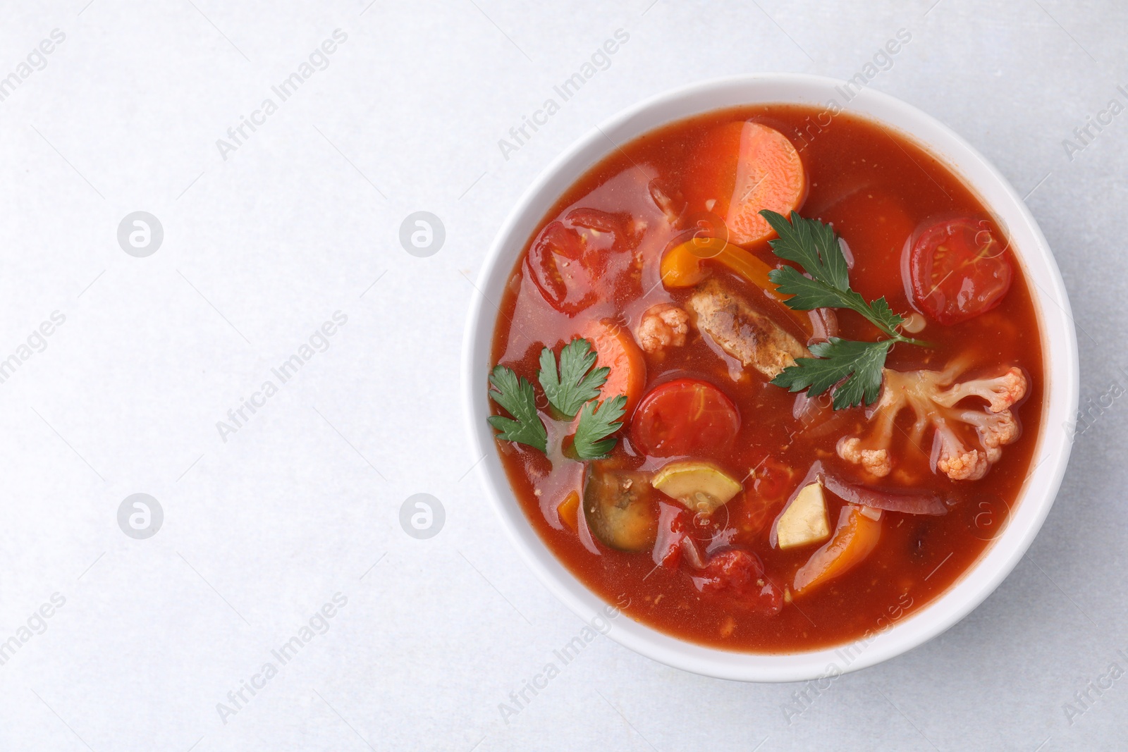 Photo of Delicious homemade stew in bowl on light table, top view. Space for text