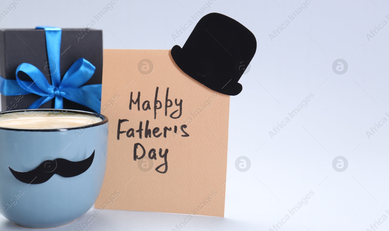 Photo of Greeting card with phrase Happy Father's Day, gift and cup of coffee on light background, space for text