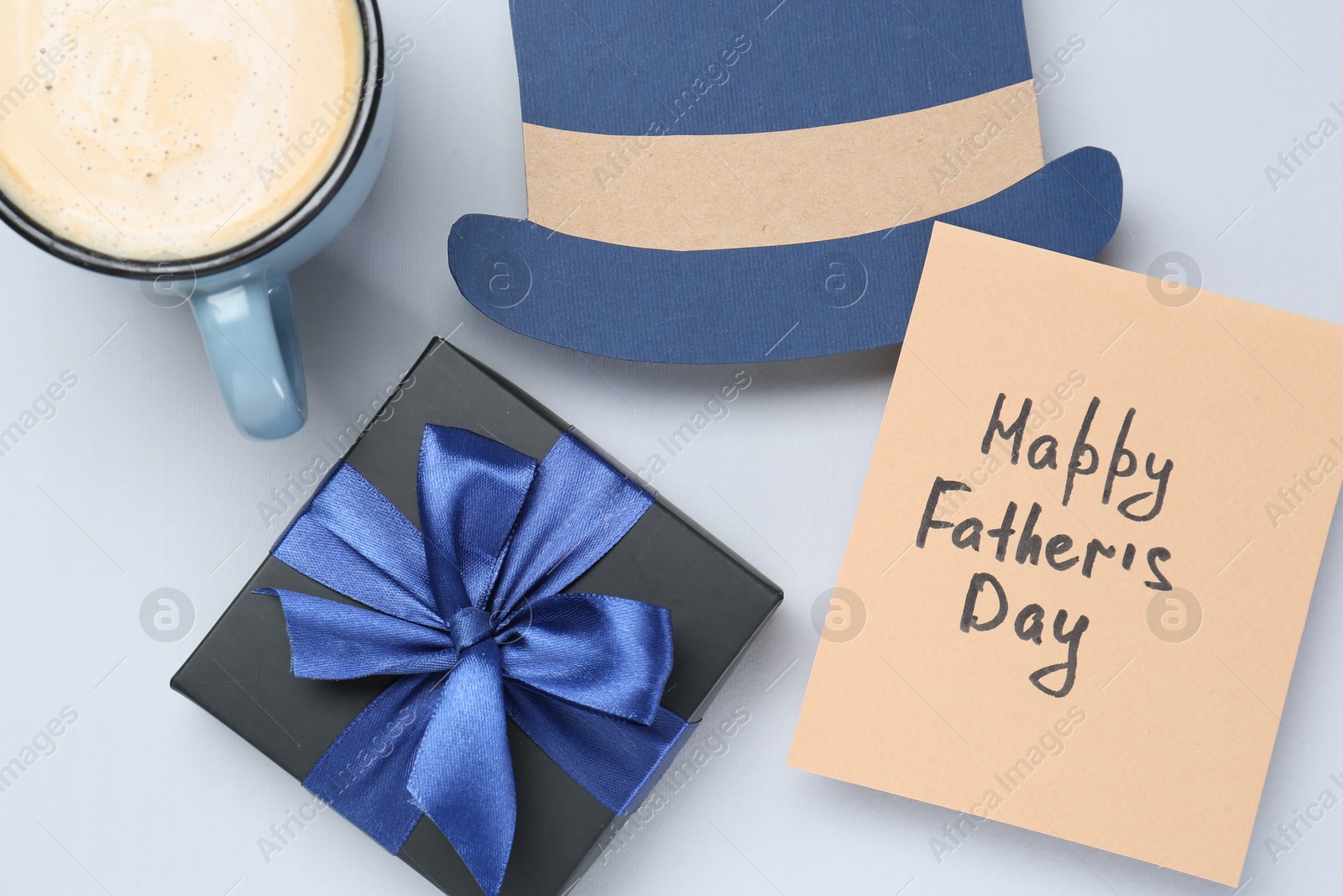 Photo of Greeting card with phrase Happy Father's Day, coffee, gift and paper hat on light background, flat lay