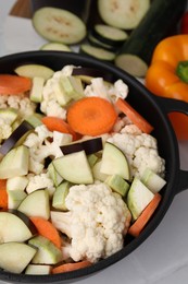 Photo of Cooking stew. Cut raw vegetables in pot on white table, closeup