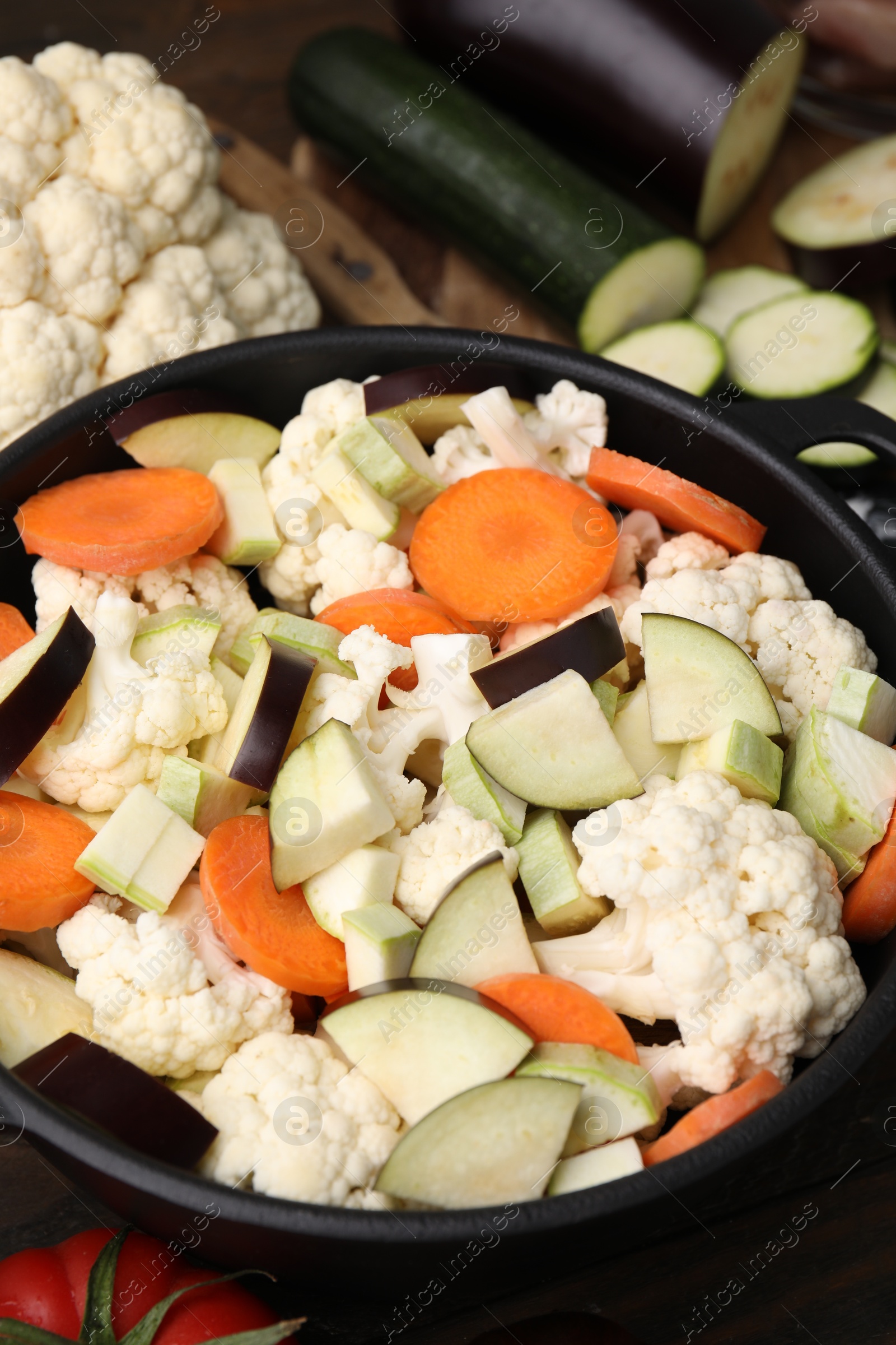 Photo of Cooking stew. Cut raw vegetables in pot on wooden table, closeup