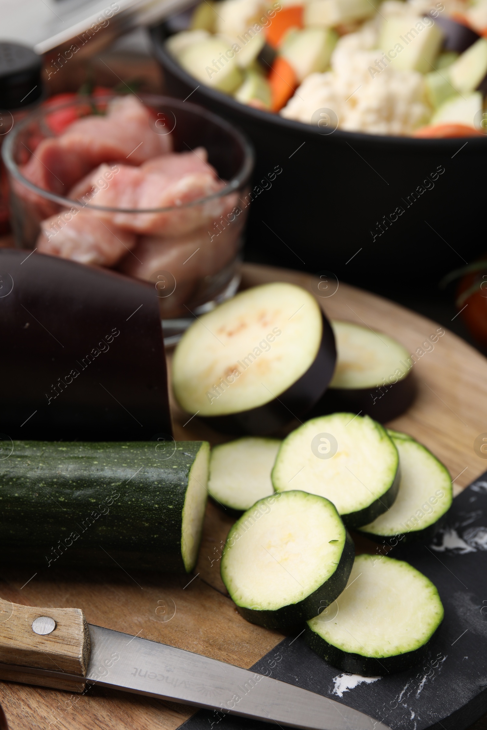 Photo of Cooking stew. Cut zucchini and eggplant on wooden table, closeup