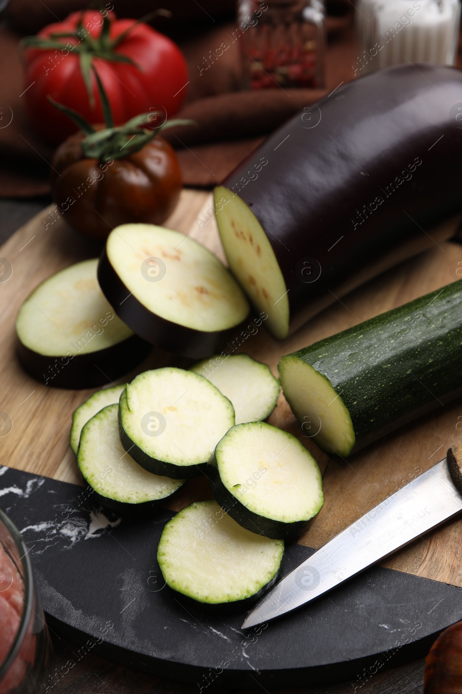 Photo of Cooking stew. Cut zucchini and eggplant on wooden table, closeup