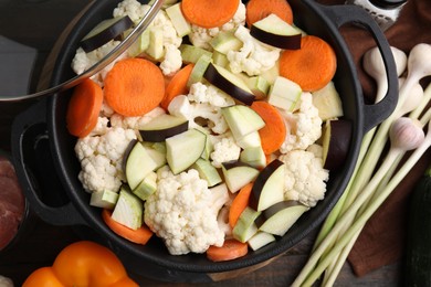 Cooking stew. Cut raw vegetables in pot on wooden table, flat lay