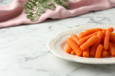 Baby carrots and leaf on white marble table, space for text