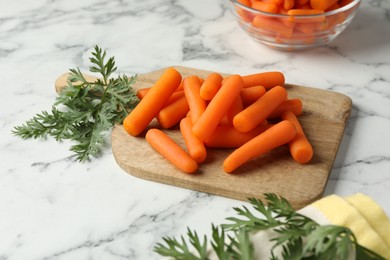 Baby carrots and green leaves on white marble table