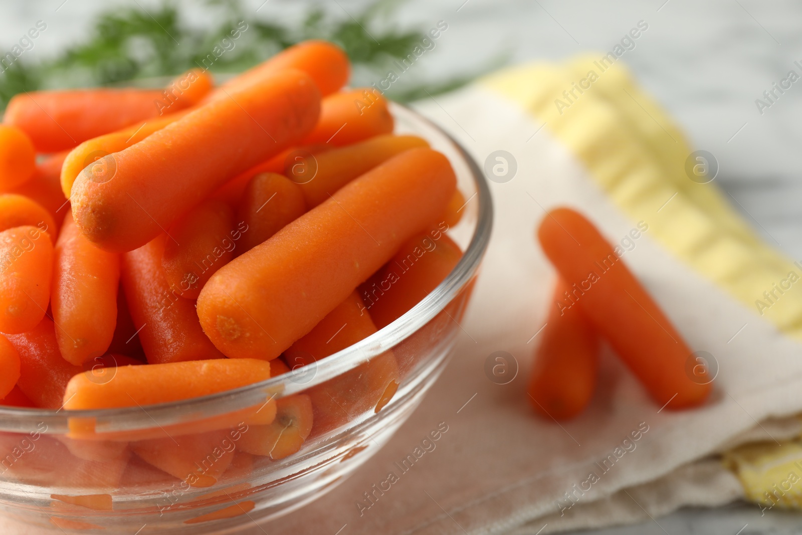 Photo of Baby carrots in bowl on table, closeup