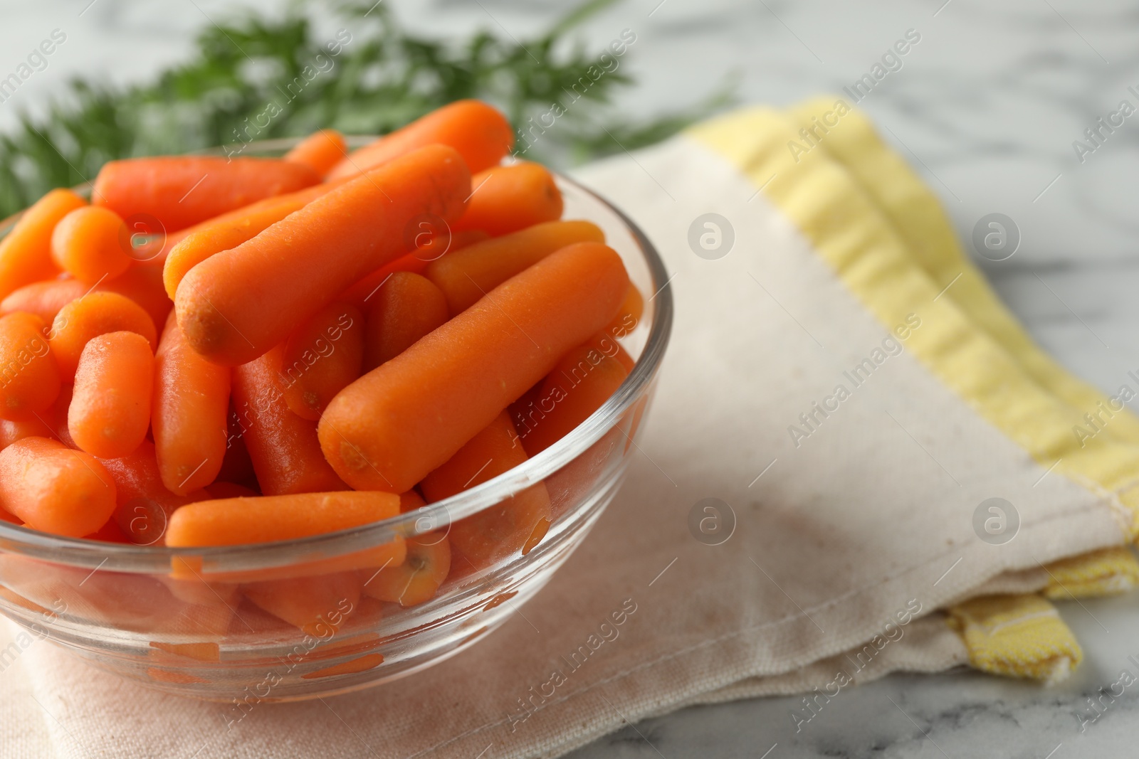 Photo of Baby carrots in bowl on white marble table, space for text