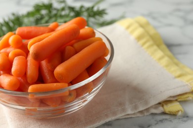 Photo of Baby carrots in bowl on white marble table, space for text