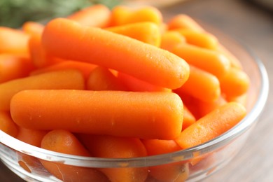 Photo of Baby carrots in bowl on table, closeup