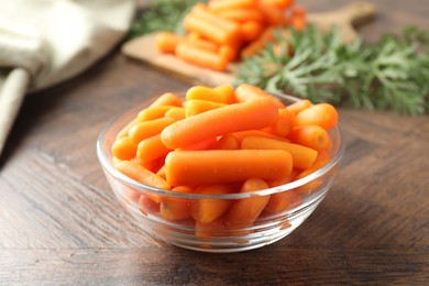 Photo of Baby carrots in bowl on wooden table