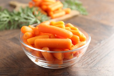 Baby carrots in bowl on wooden table