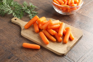 Baby carrots green leaves on wooden table