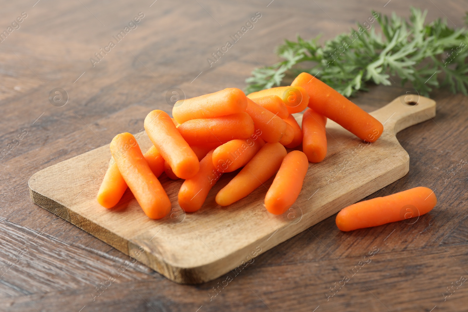 Photo of Baby carrots green leaves on wooden table