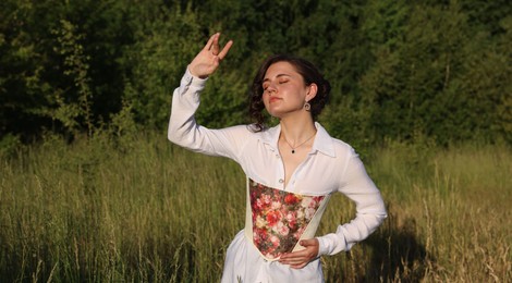 Beautiful woman in stylish corset posing outdoors on sunny day