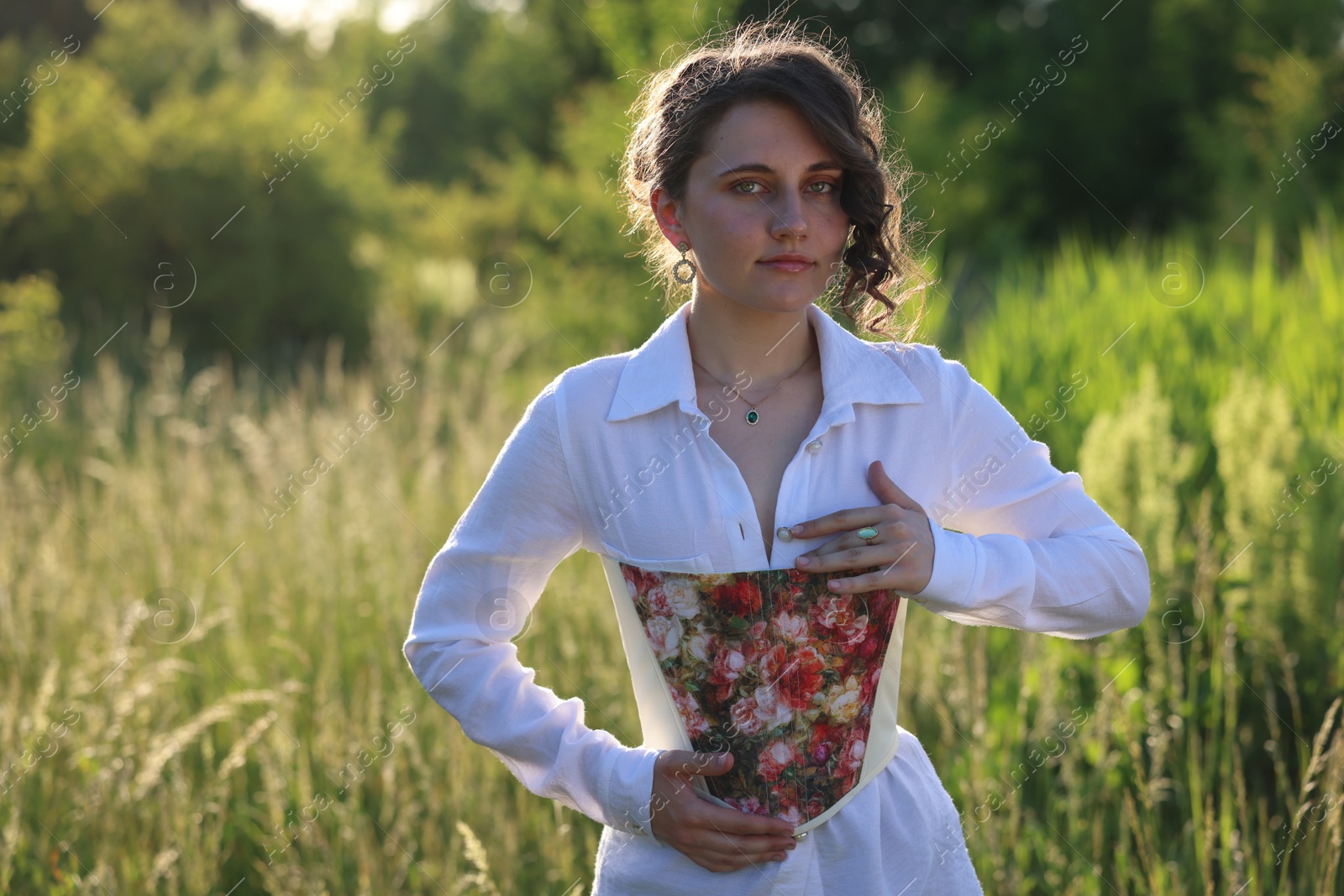 Photo of Beautiful woman in stylish corset posing outdoors on sunny day. Space for text