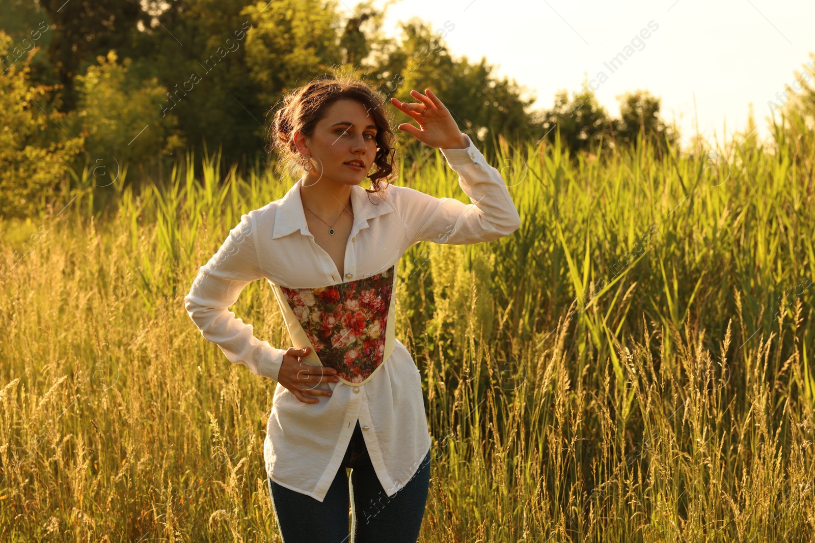 Photo of Beautiful woman in stylish corset posing outdoors on sunny day. Space for text